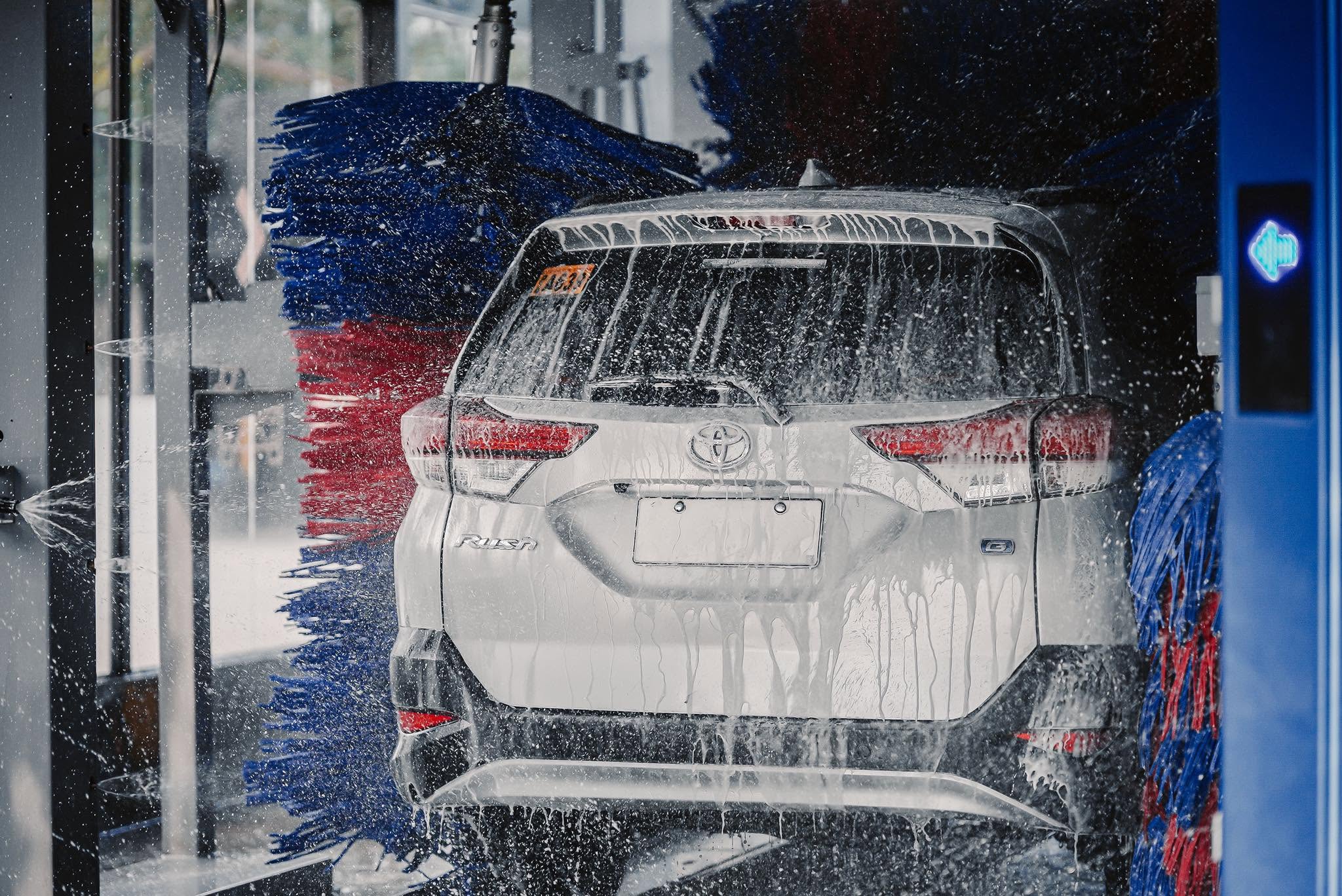 Rear of a white SUV being cleaned by the wash brushes